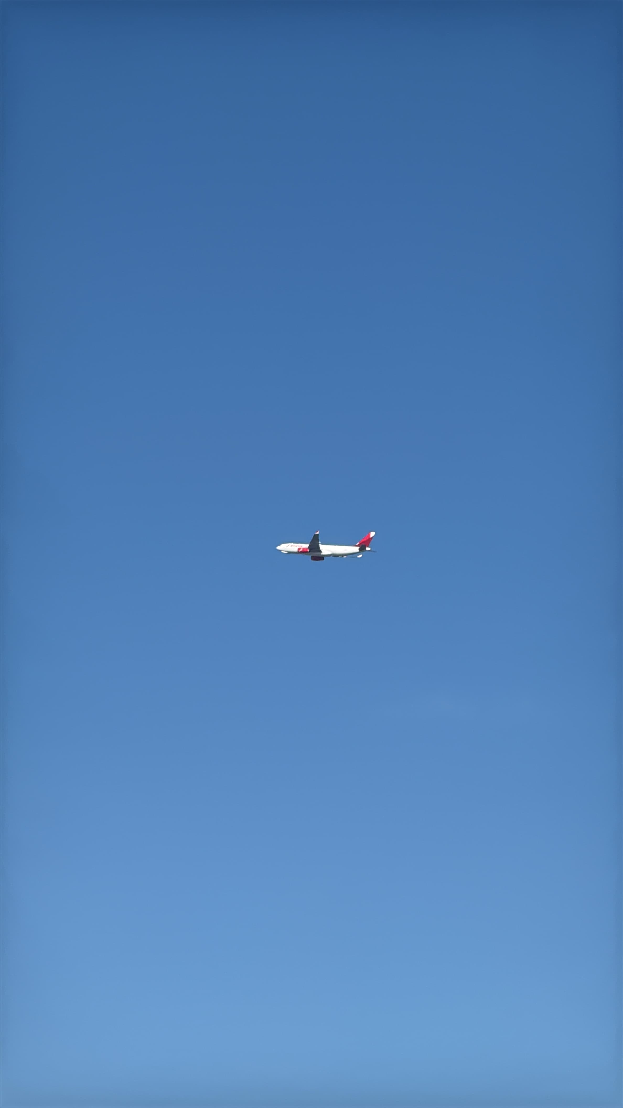 Airbus A330-200 small against a clear blue sky.