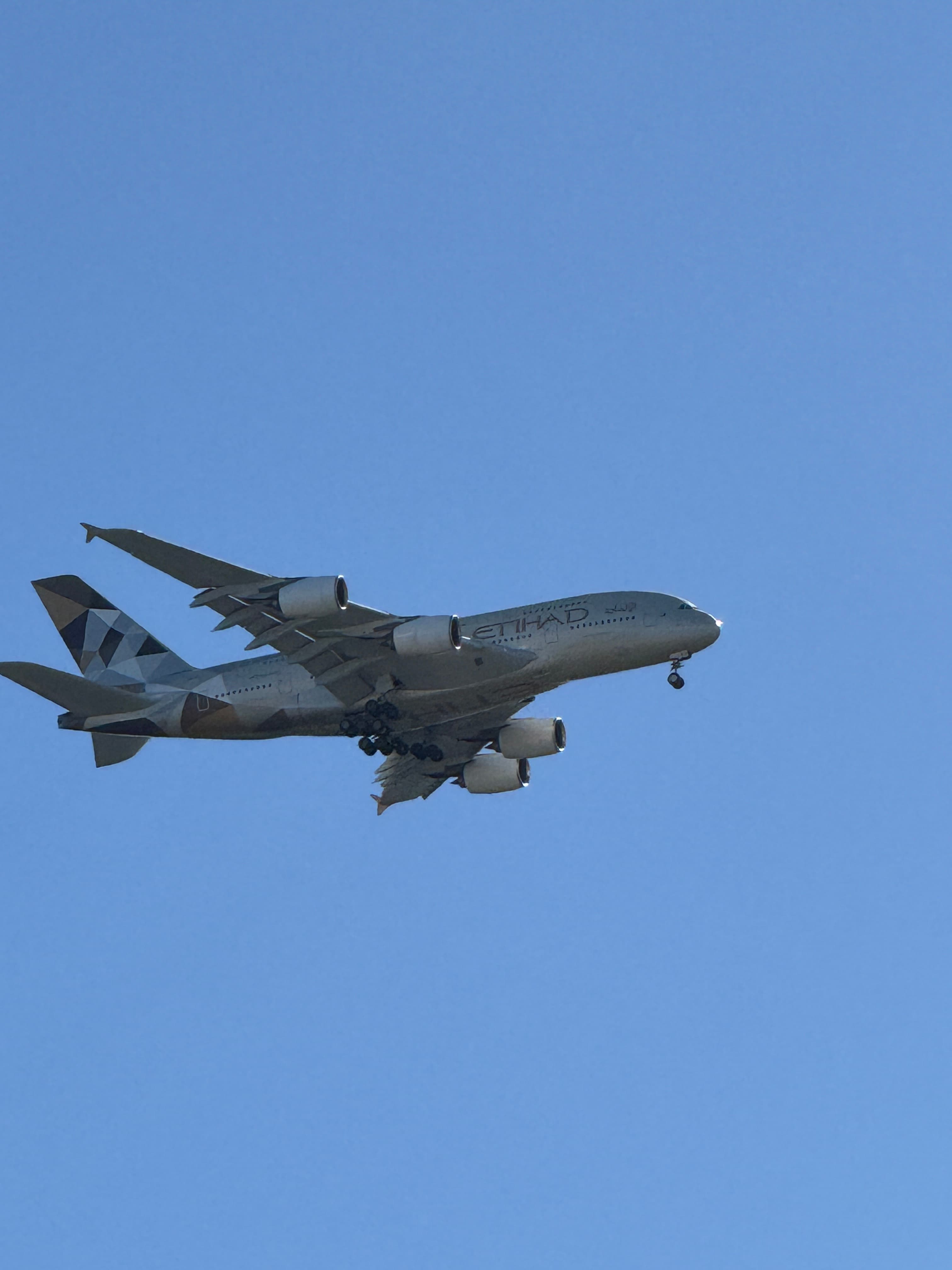 Airbus A380-800 with landing gear down against a blue sky.