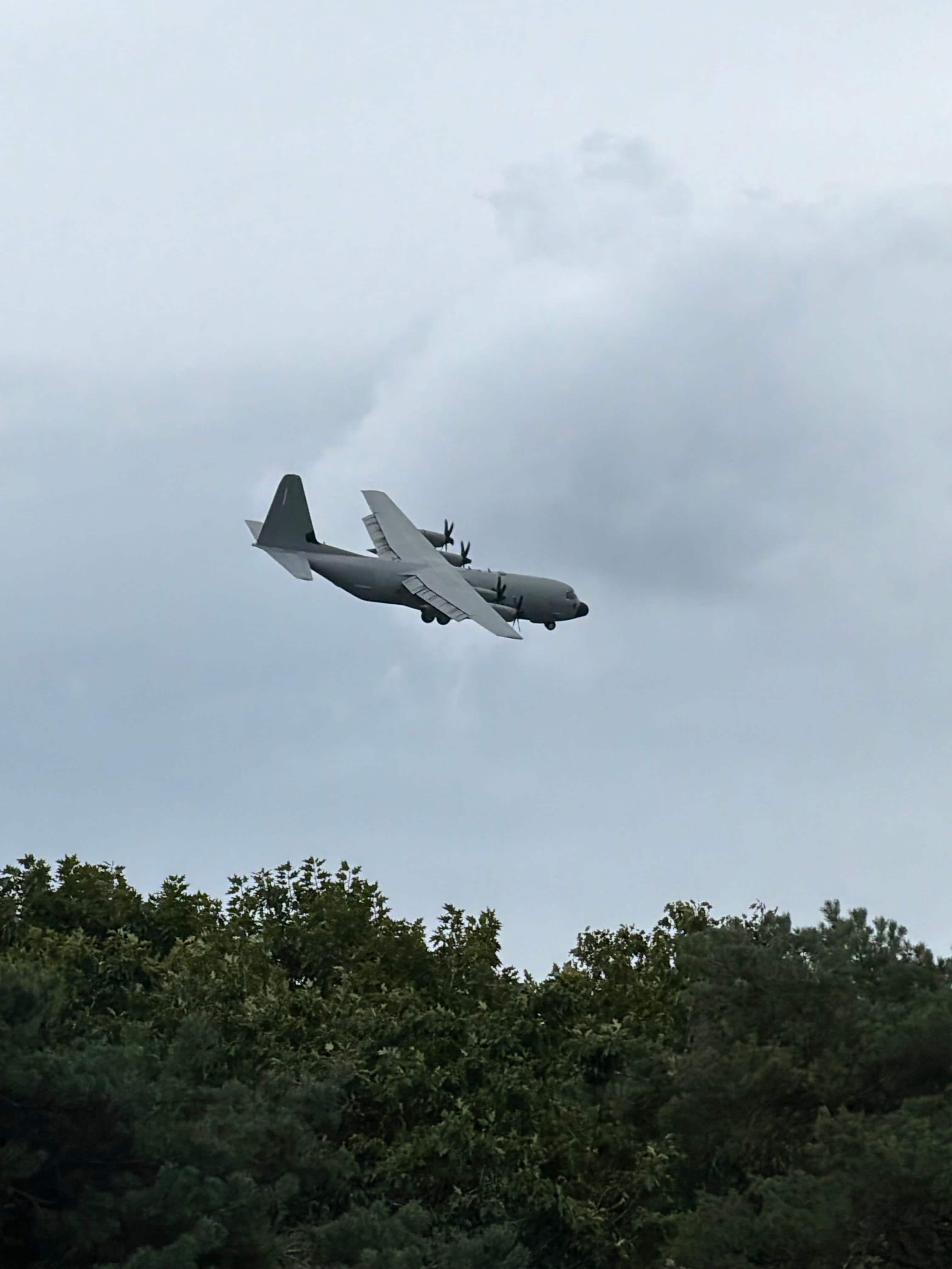 Italian Air Force C-130J 46-57 flying above treetops under cloud