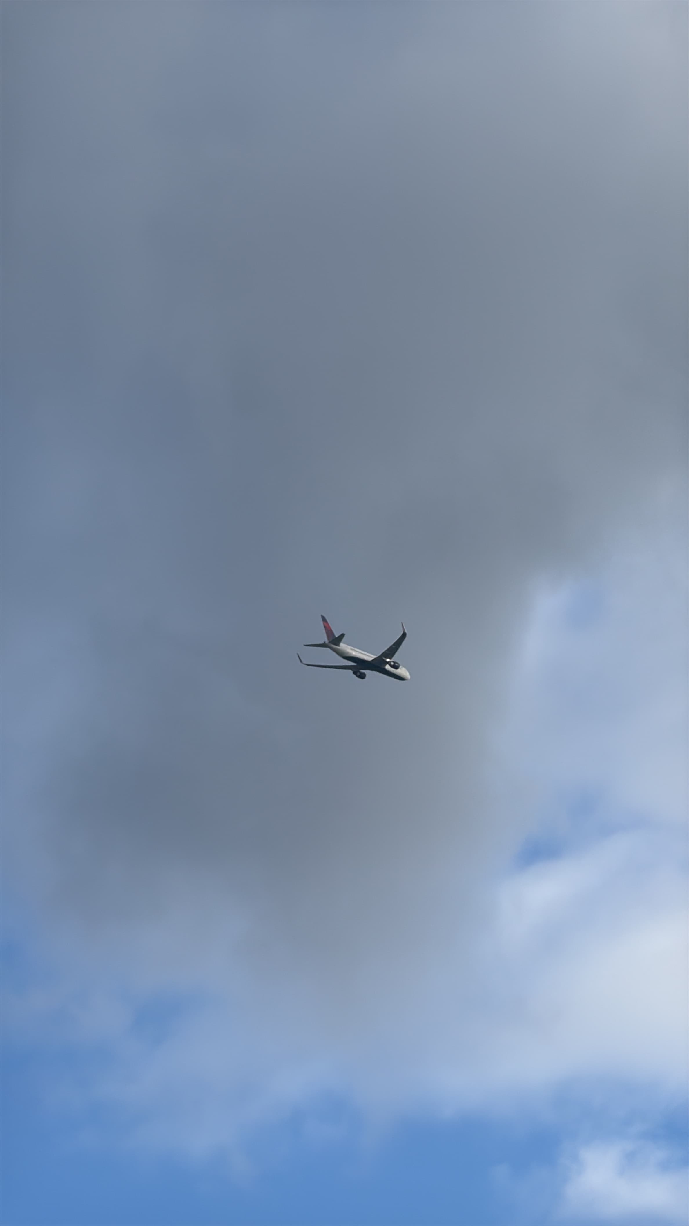 Boeing 767-300 against a grey cloud bank, viewed from below.