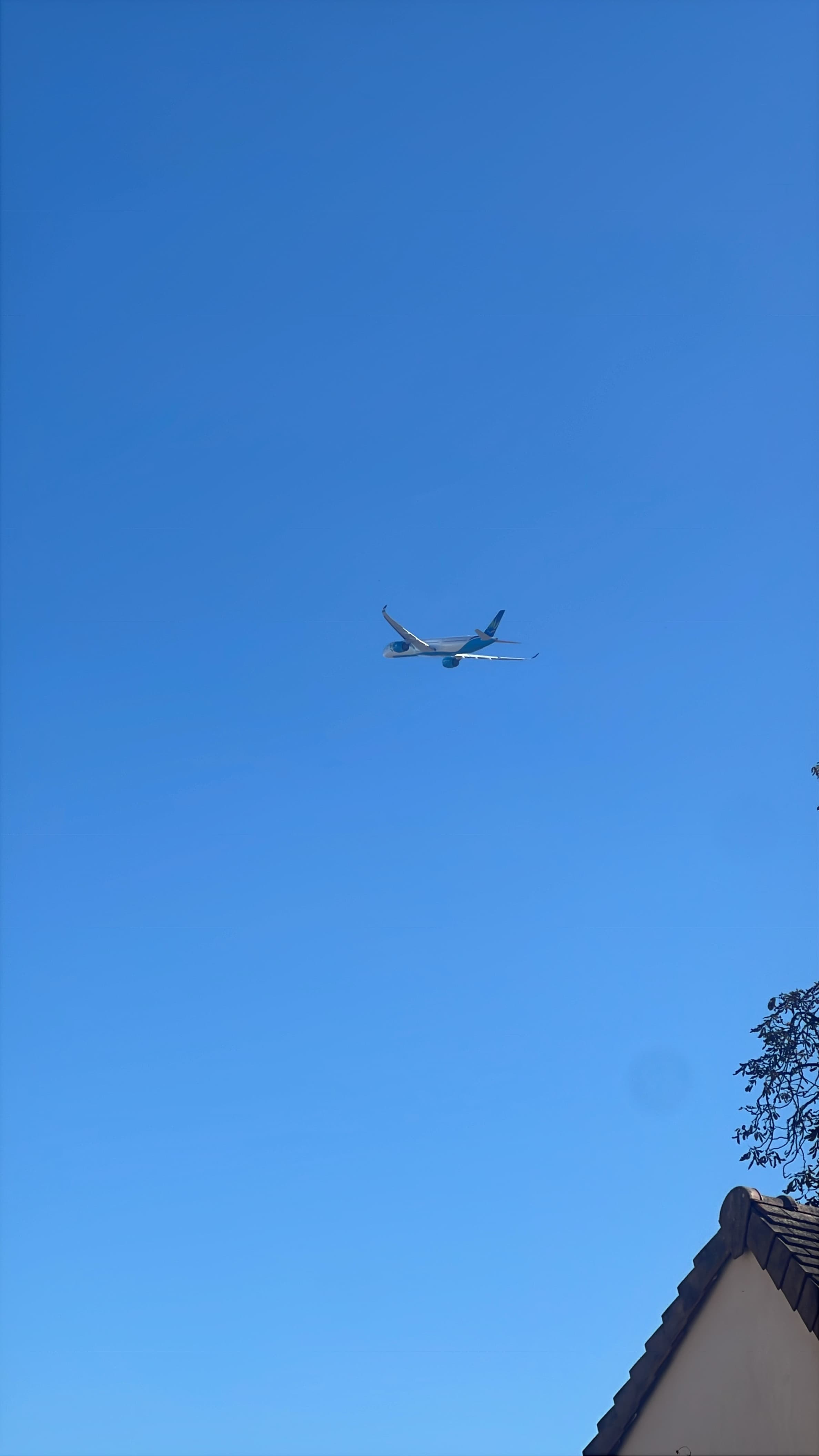 Airbus A350-1000 small against a clear blue sky, viewed from below.