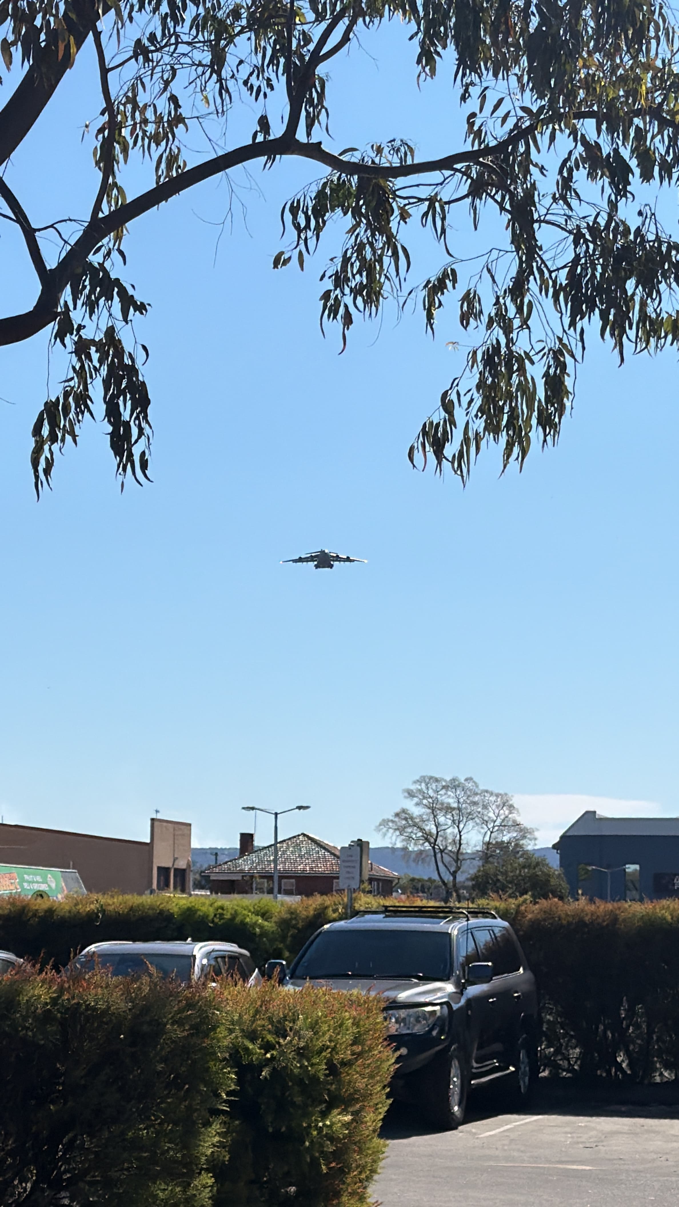 Boeing C-17 Globemaster III approaching above trees and rooftops