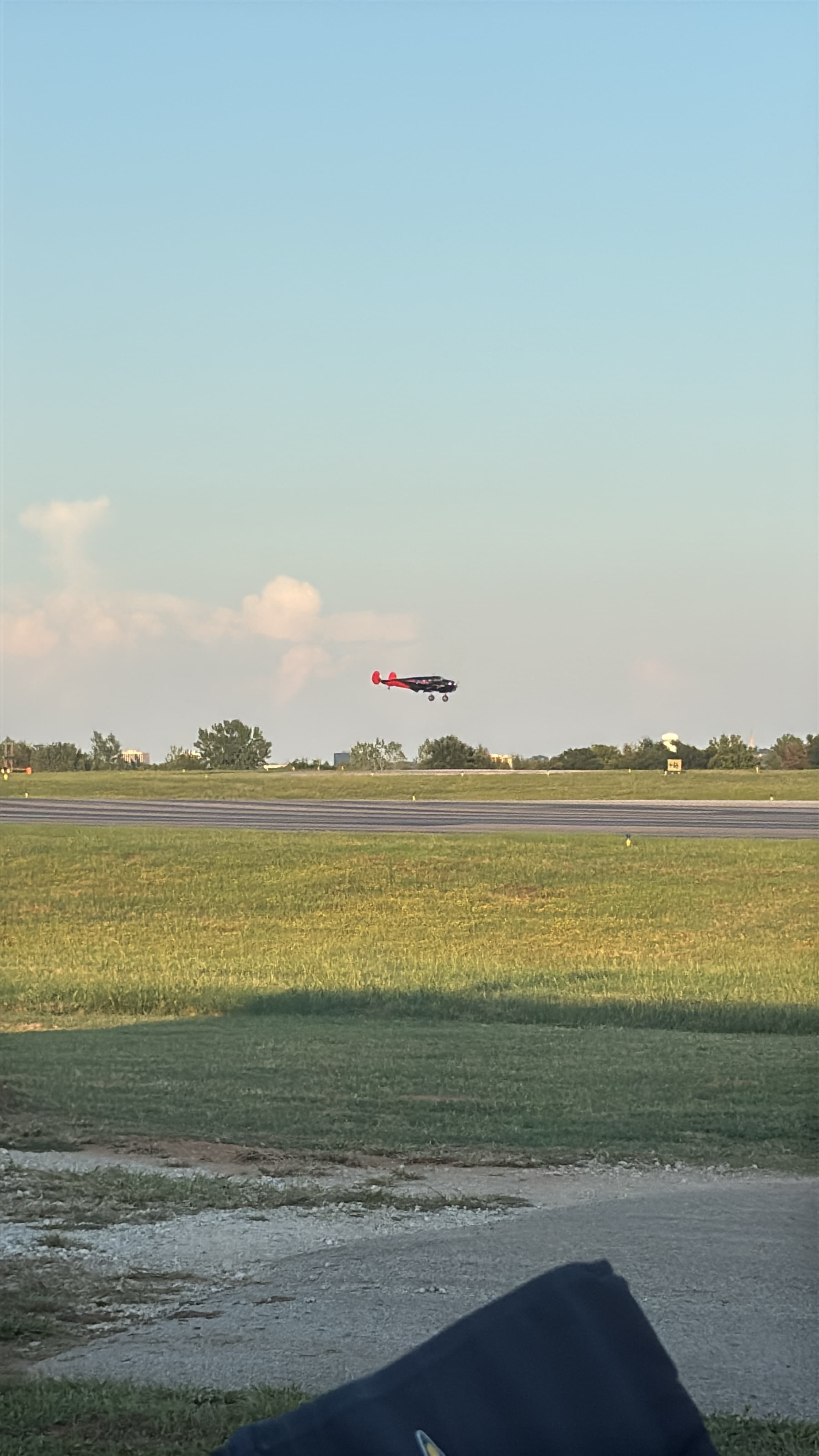 Beech 18 flying low above a runway and grass field